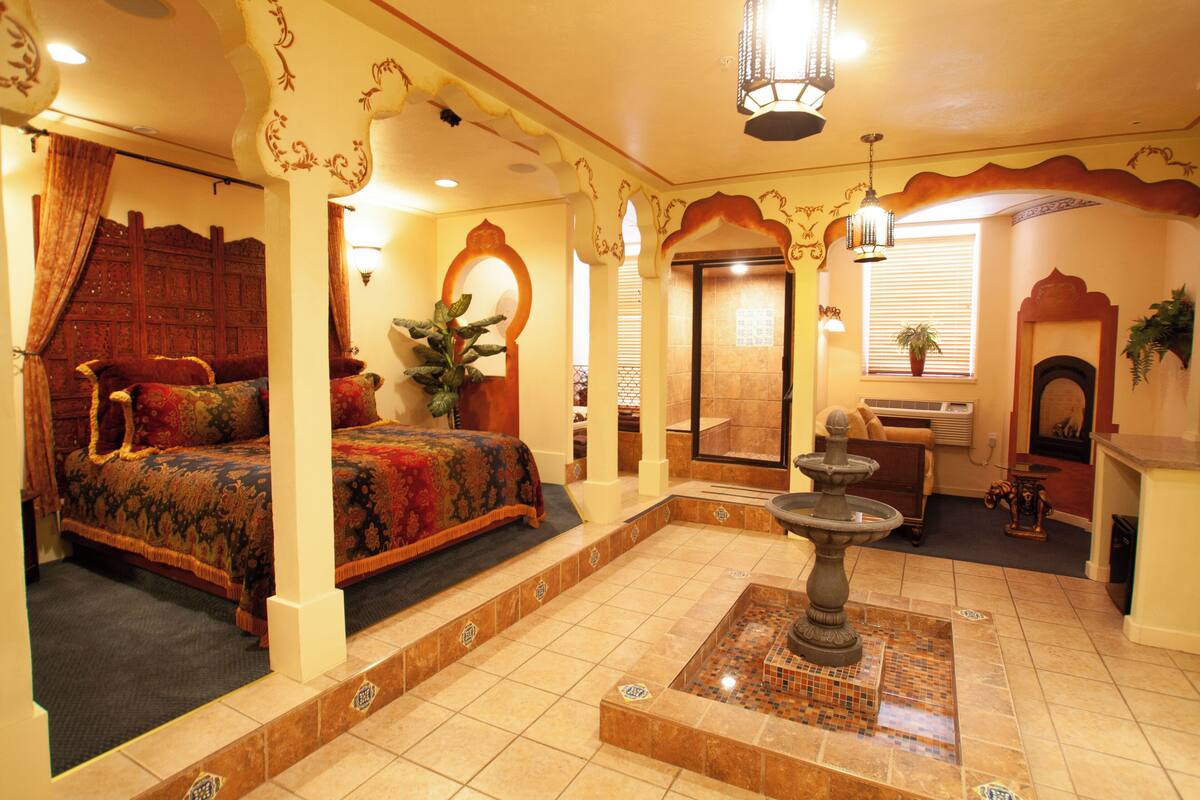 A traditional room with a bed, a small fountain, and a fireplace.