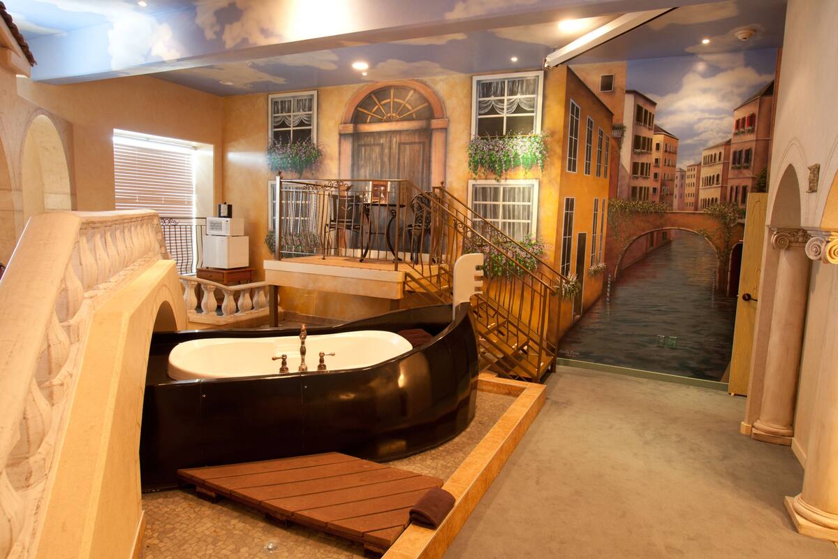 A luxurious bathroom with a freestanding bathtub, a wooden bench, and a small sink.