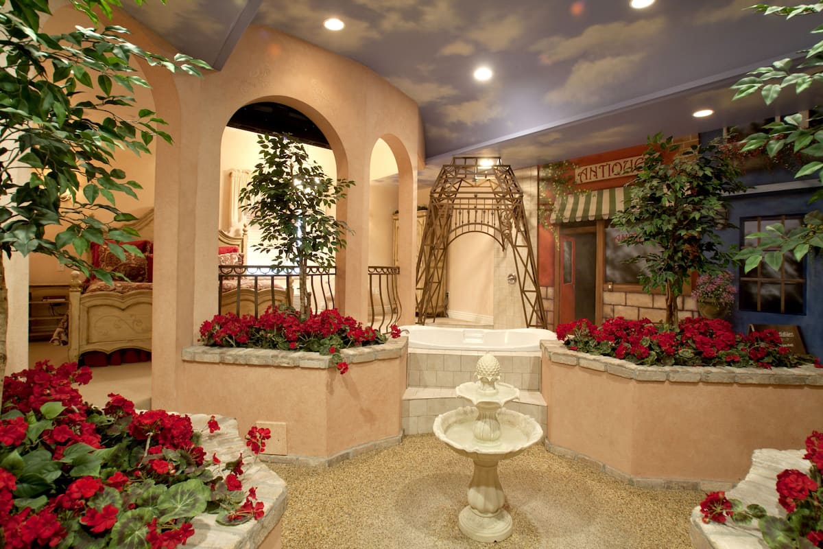 A courtyard with a fountain, red flowers, and a spa area.