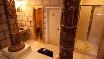Un baño con columnas de estilo egipcio, una ducha y una puerta con picaporte.