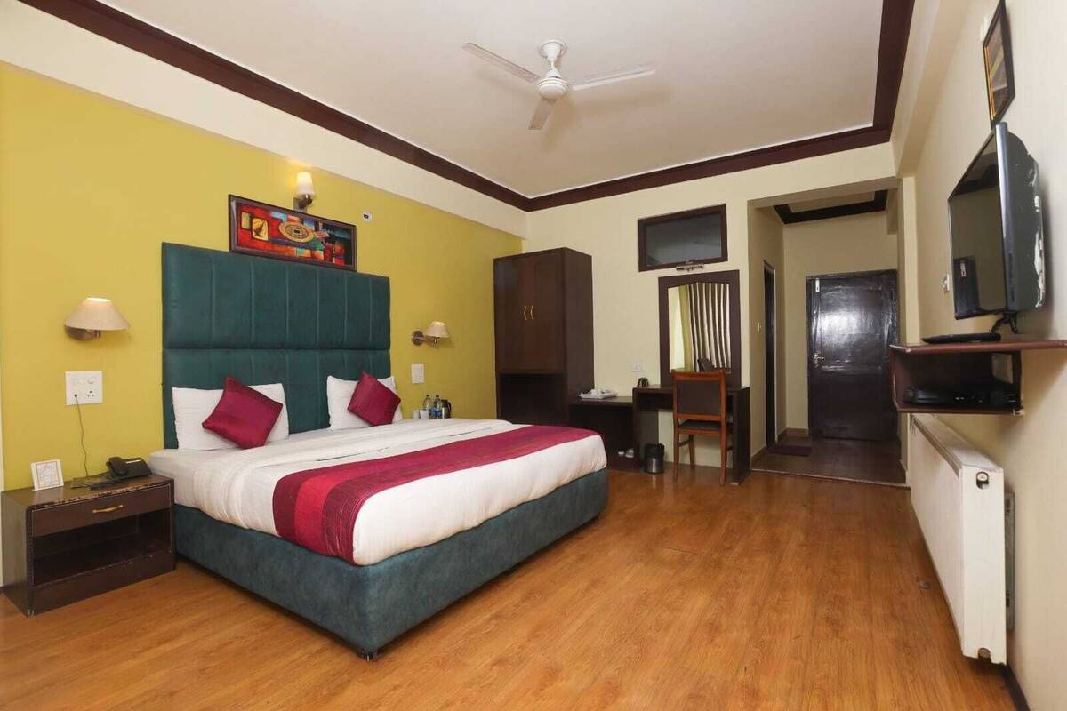 A hotel room with a bed, desk, chair, TV, and a ceiling fan.