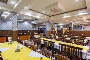 Um restaurante amplo com várias mesas e cadeiras, um balcão e uma parede com padrão.