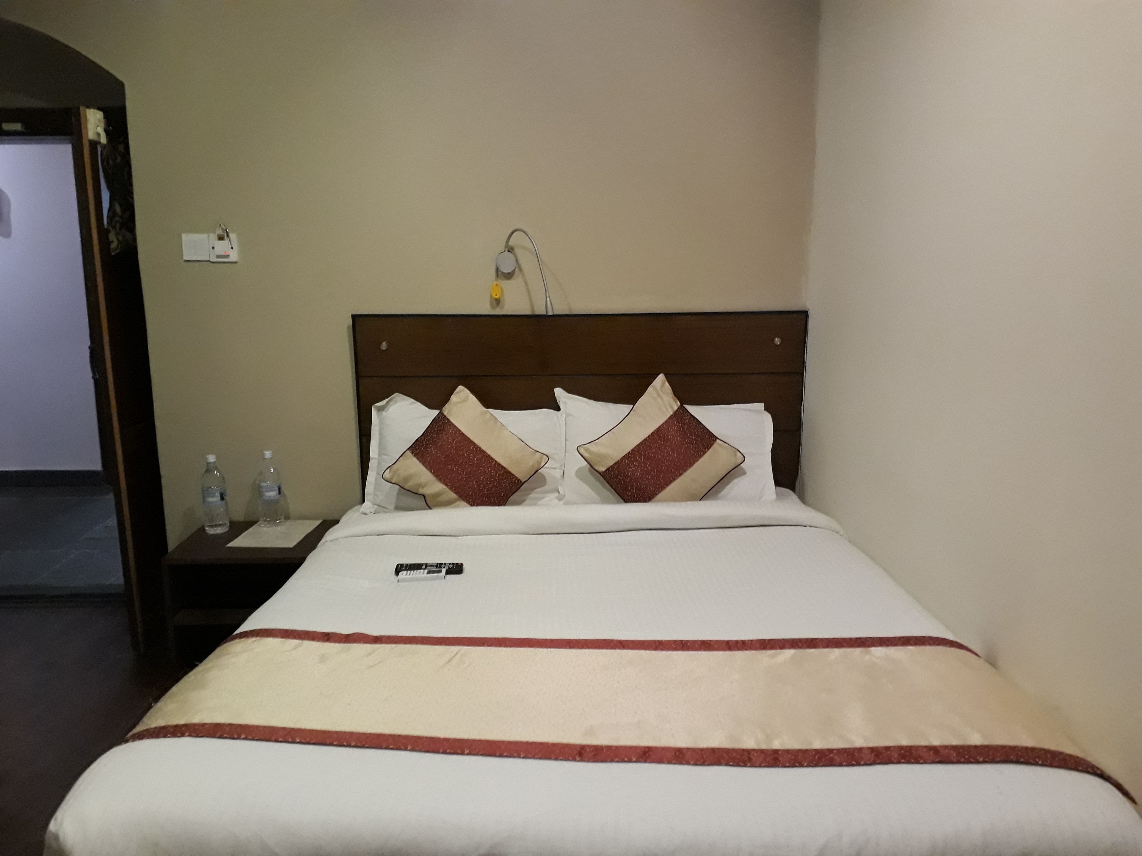 Une chambre d’hôtel avec un lit, deux oreillers, une table de chevet avec un téléphone et une prise électrique au mur.