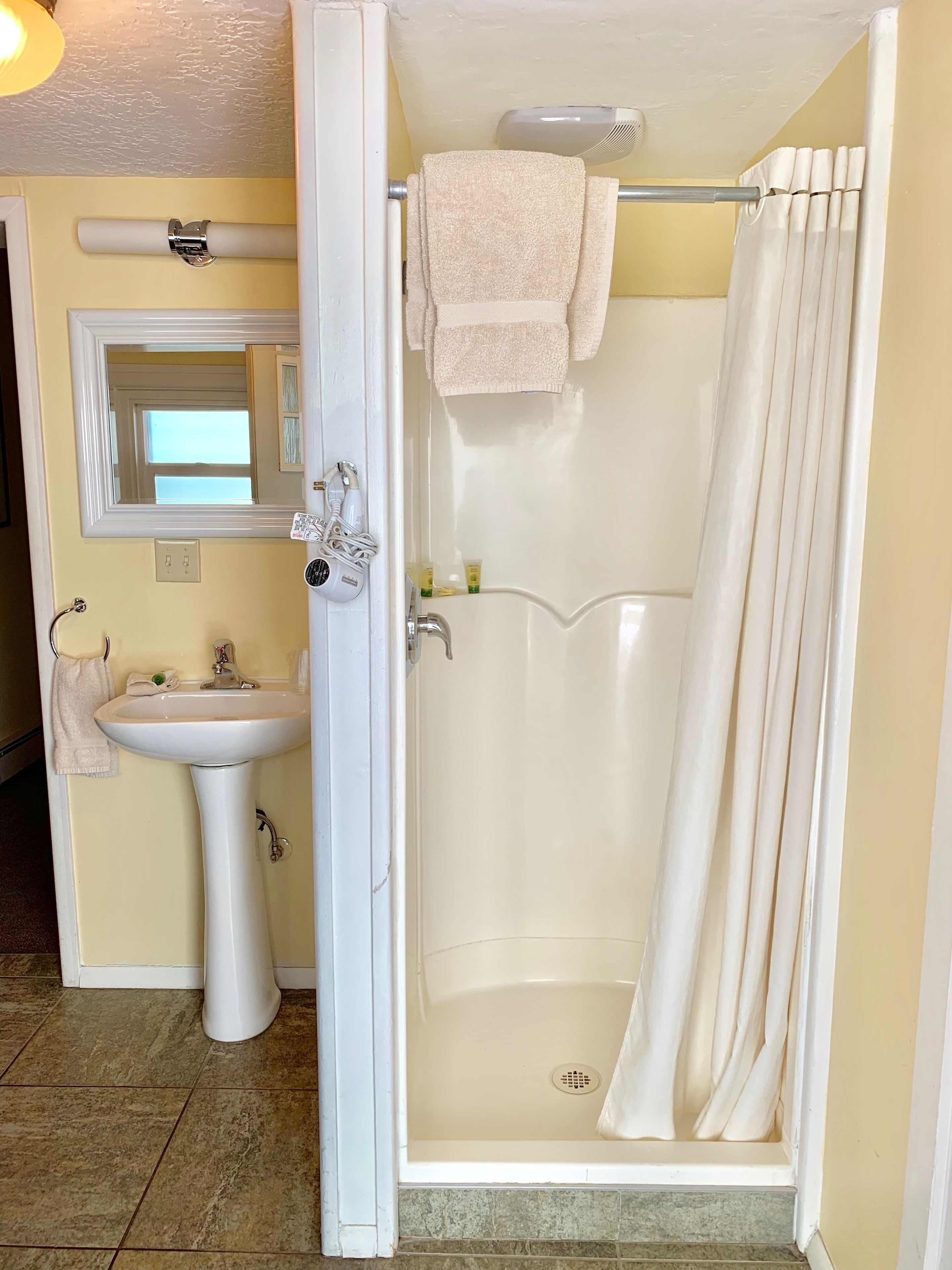 A bathroom with a shower, sink, and mirror.