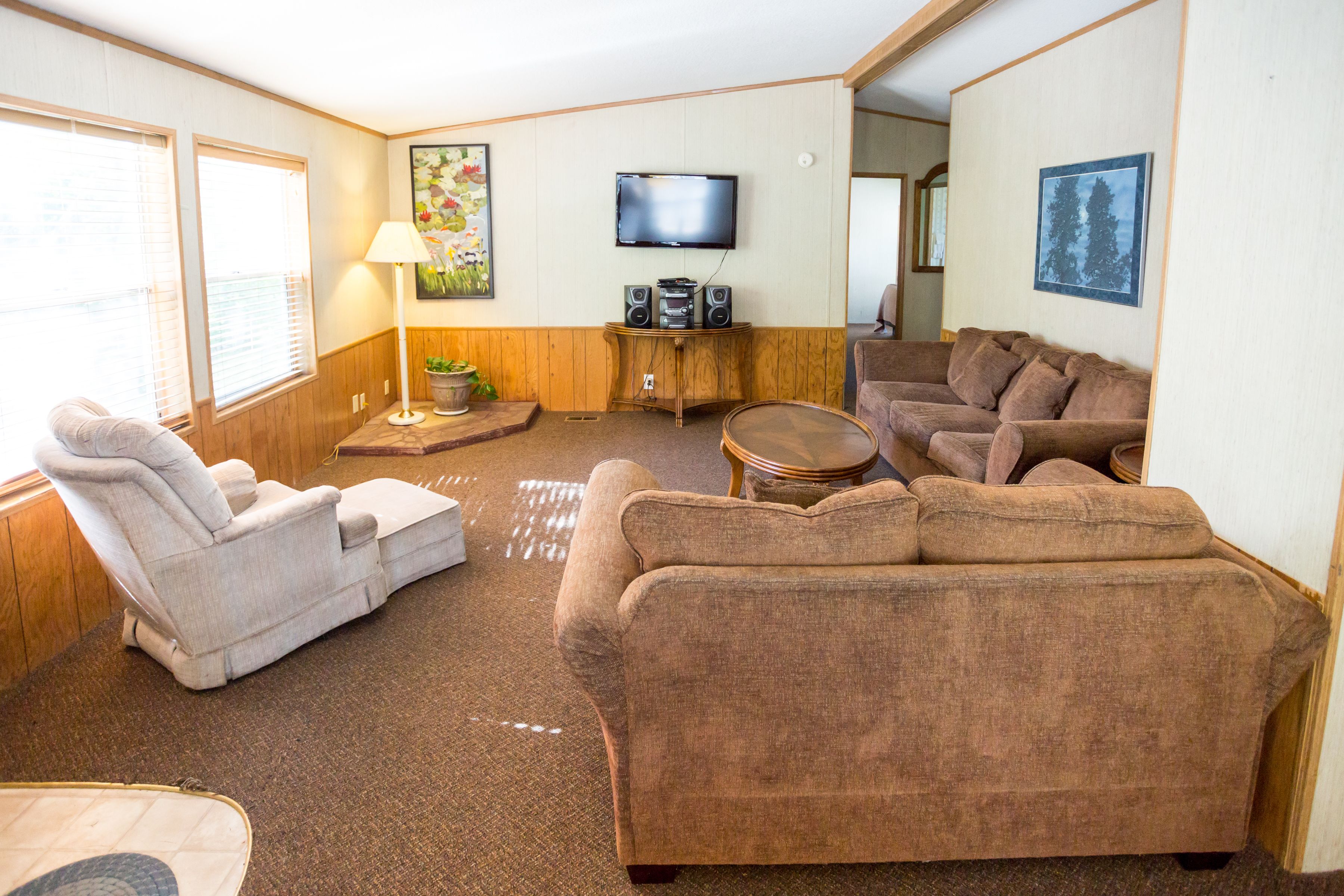 A living room with a sofa, armchair, and a television on a wooden cabinet.