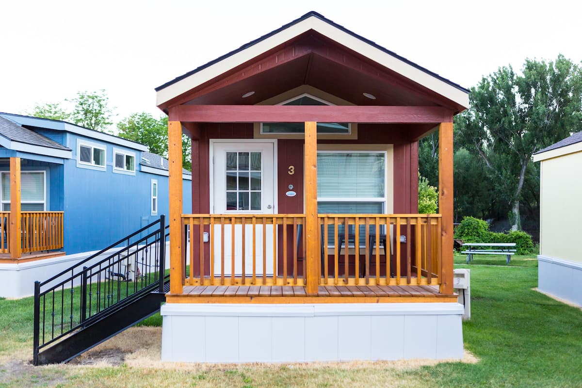 A small, single-story cabin with a wooden deck and a white door marked with the number 3.