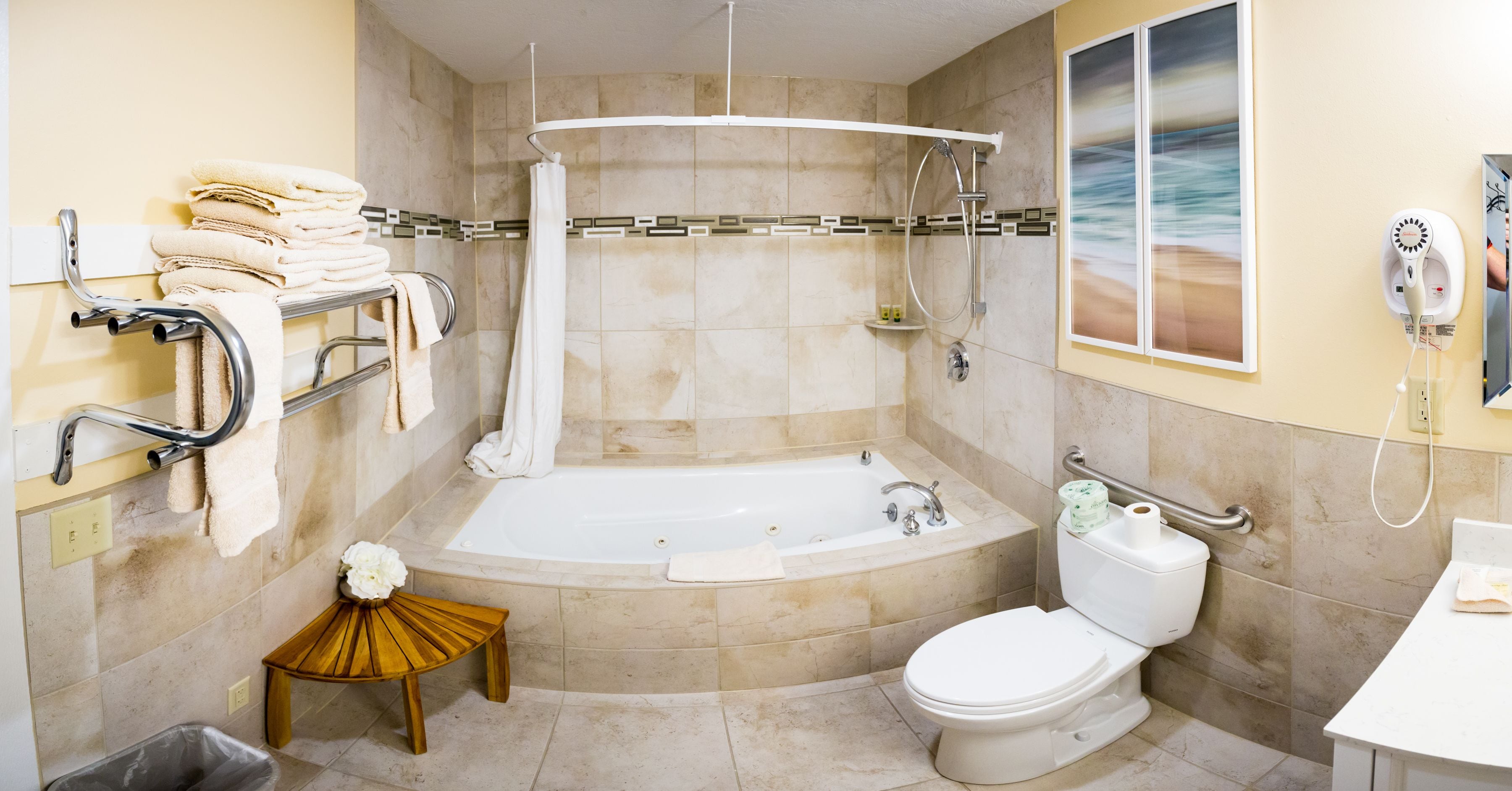 A bathroom with a bathtub, toilet, and a small wooden stool.