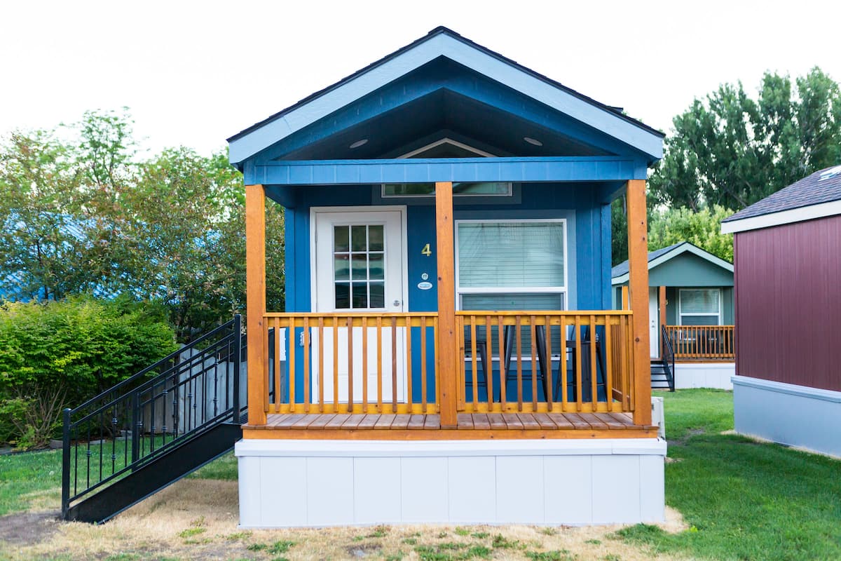 A small, single-story cabin with a wooden deck and a porch.