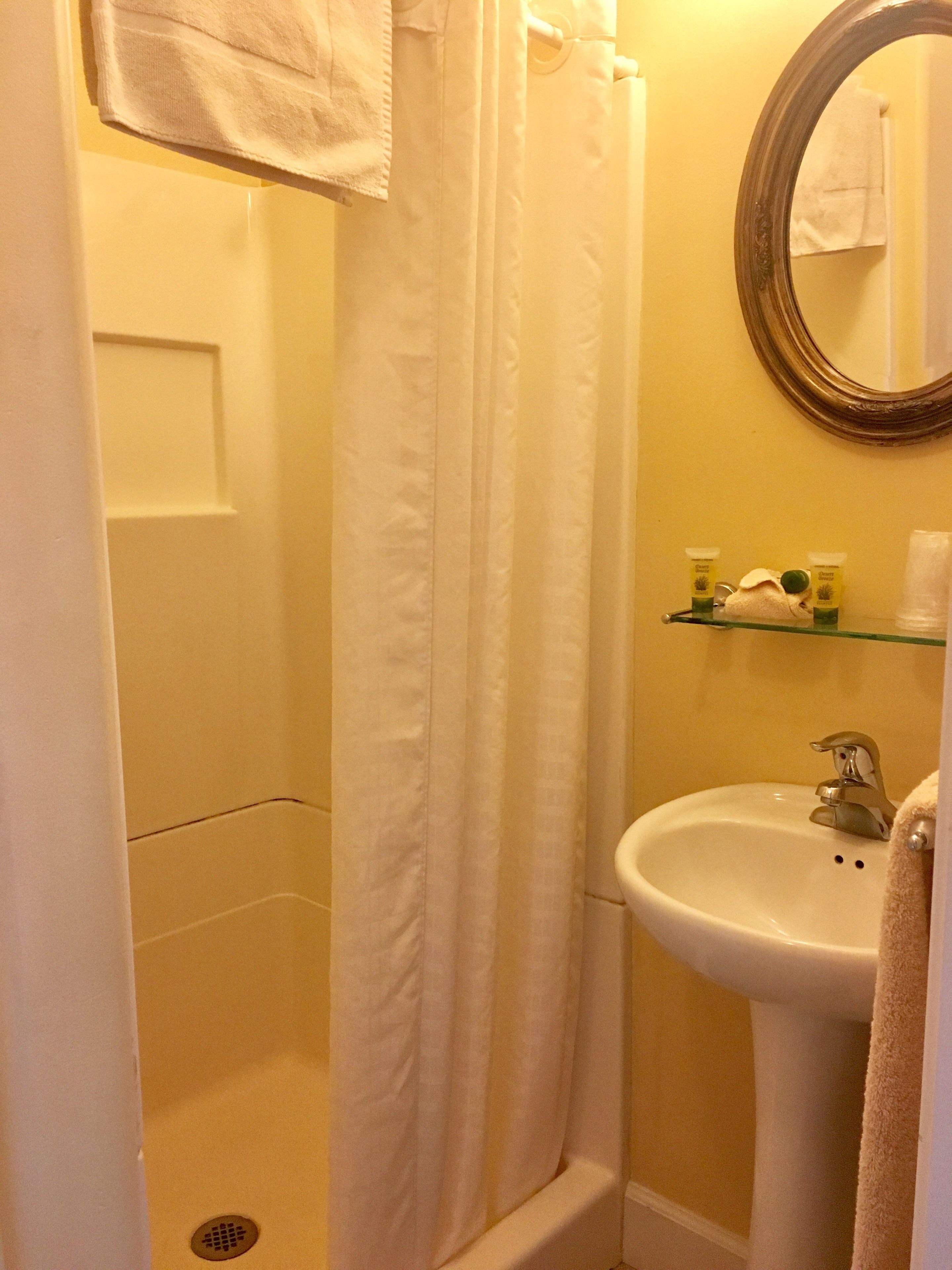 A bathroom with a shower curtain, a sink, and a mirror.