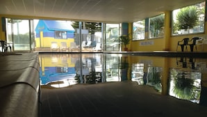 Una piscina interior con reflejos nítidos, un cartel que indica 'No Diving' y vistas de un edificio azul en el exterior.