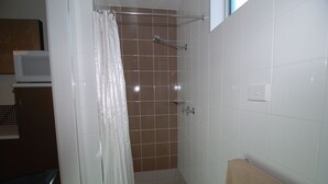 Ducha con cortina blanca, toallero y pared de azulejos.