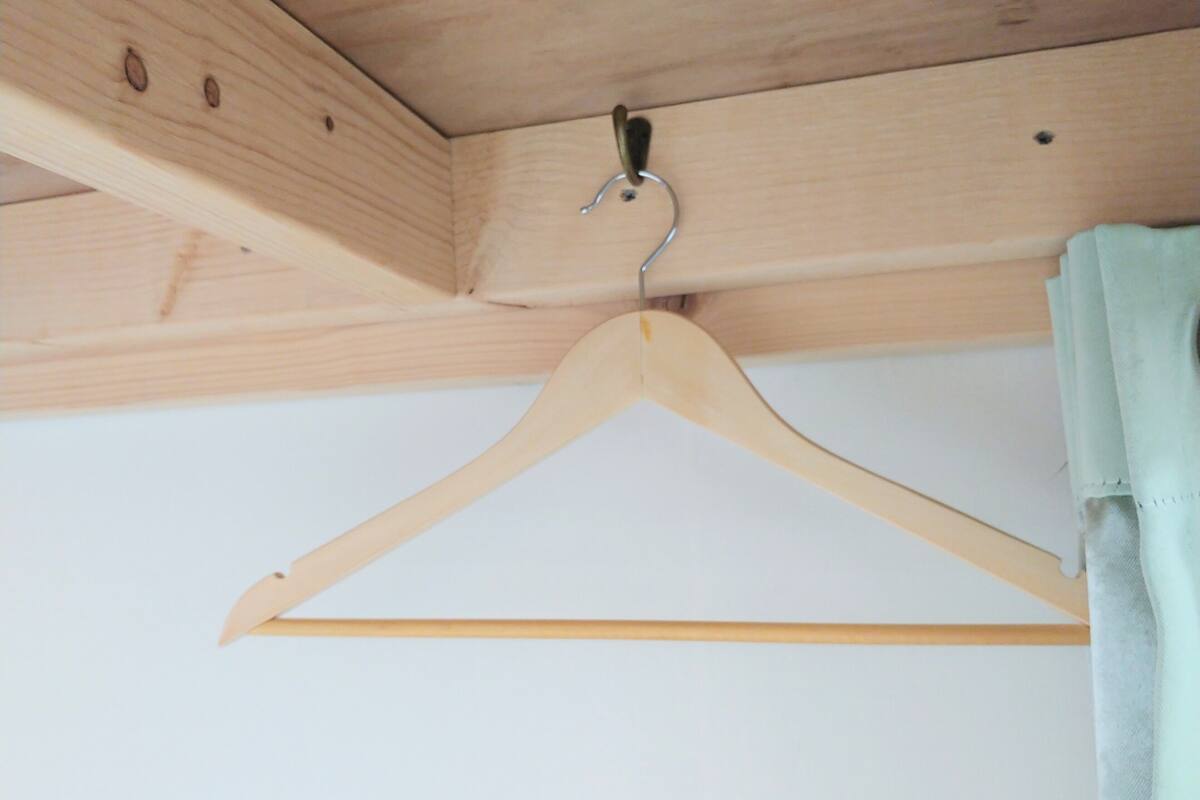 Un perchero de madera colgando de una viga del techo en una habitación con paredes blancas.