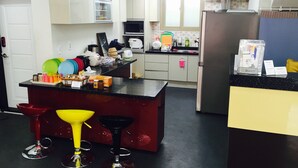 A modern kitchen with a central island, bar stools, and various kitchen appliances.