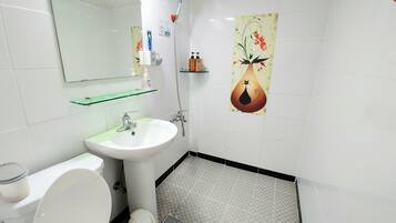 Un bagno con il water, lavandino, doccia e una parete decorativa.