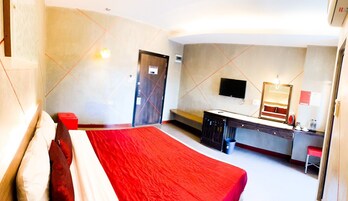 Una habitación de hotel moderna con una cama grande, un escritorio con espejo y un televisor en la pared.