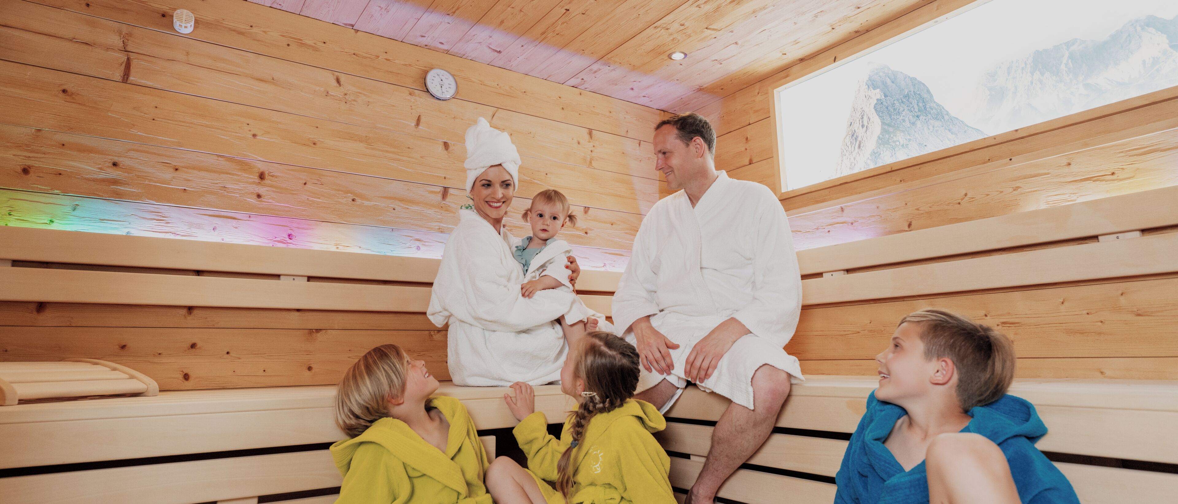 Un sauna avec des bancs en bois et une grande fenêtre donnant sur la montagne.