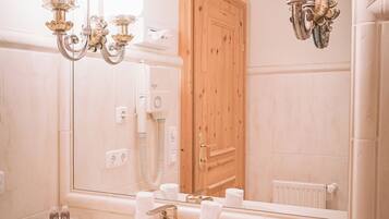 Une salle de bain avec un grand miroir, un lavabo, un lustre et une porte en bois.