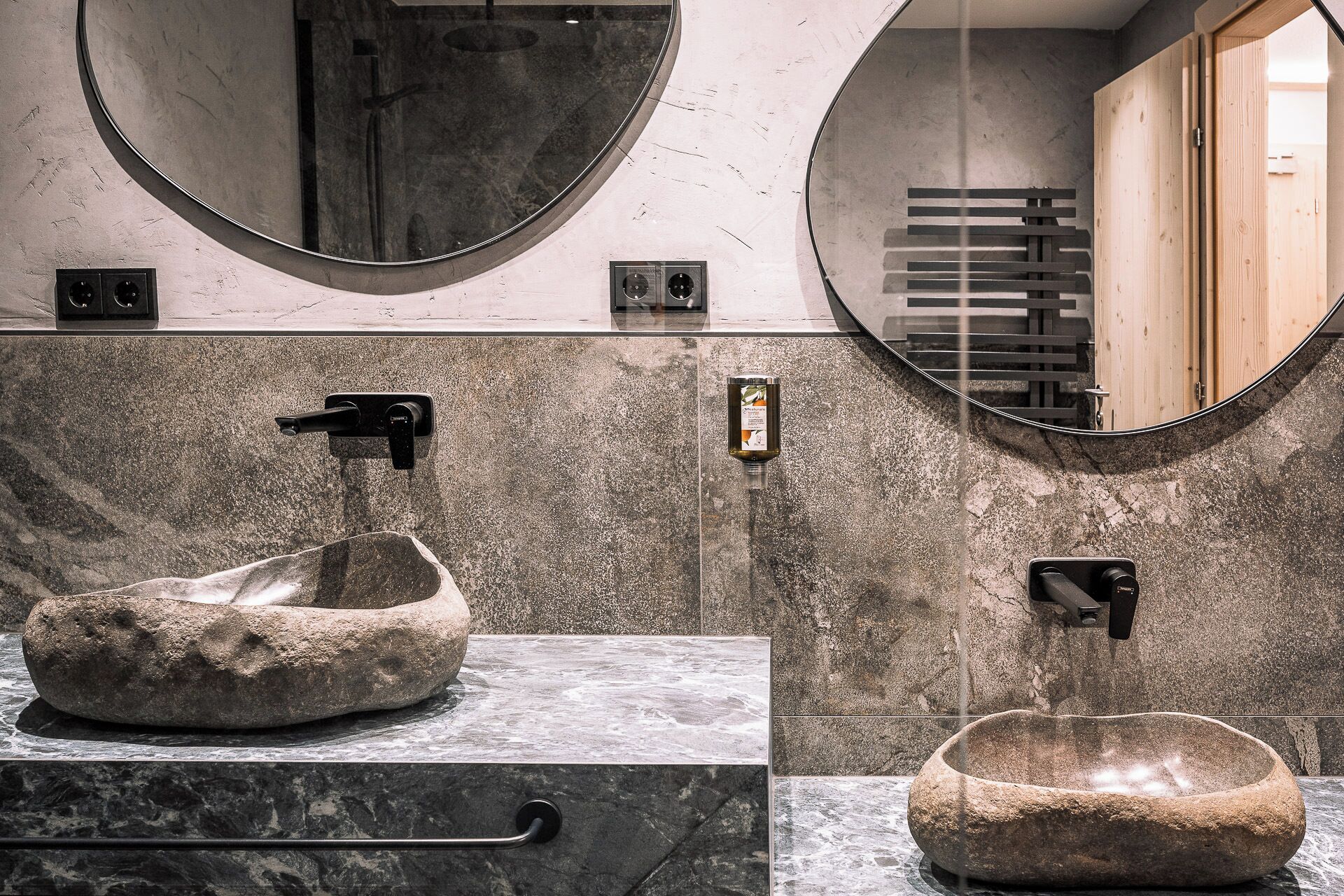 Ein Badezimmer mit einem Steinkonstruktion als Waschbecken, einem Spiegel und einer Holztür.