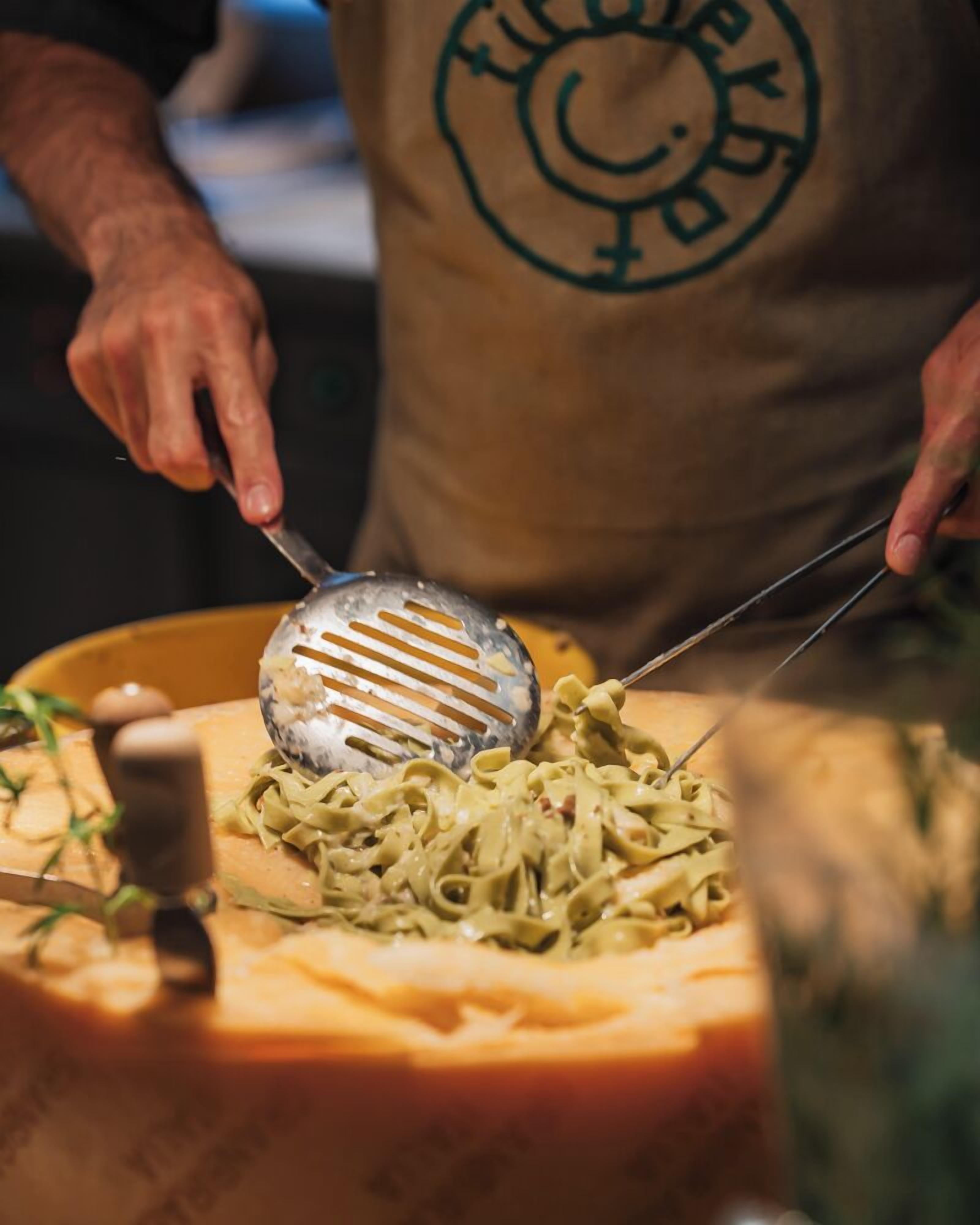 Una persona sirve pasta en un plato con una cuchara ranurada.