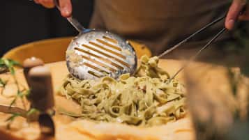 Una persona sirve pasta en un plato con una cuchara ranurada.