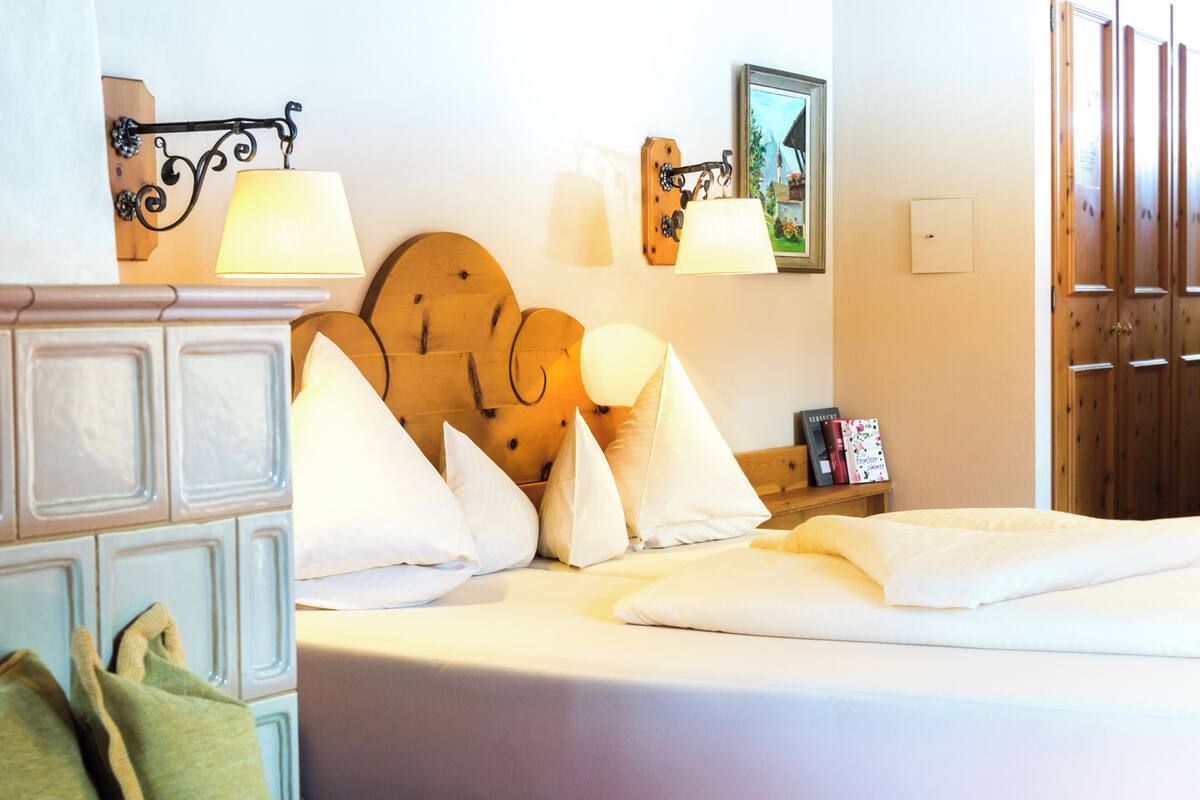 Ein Hotelzimmer mit Bett, Kissen, einem Nachttisch, Wandlampen und einem Holz-Kopfteil.