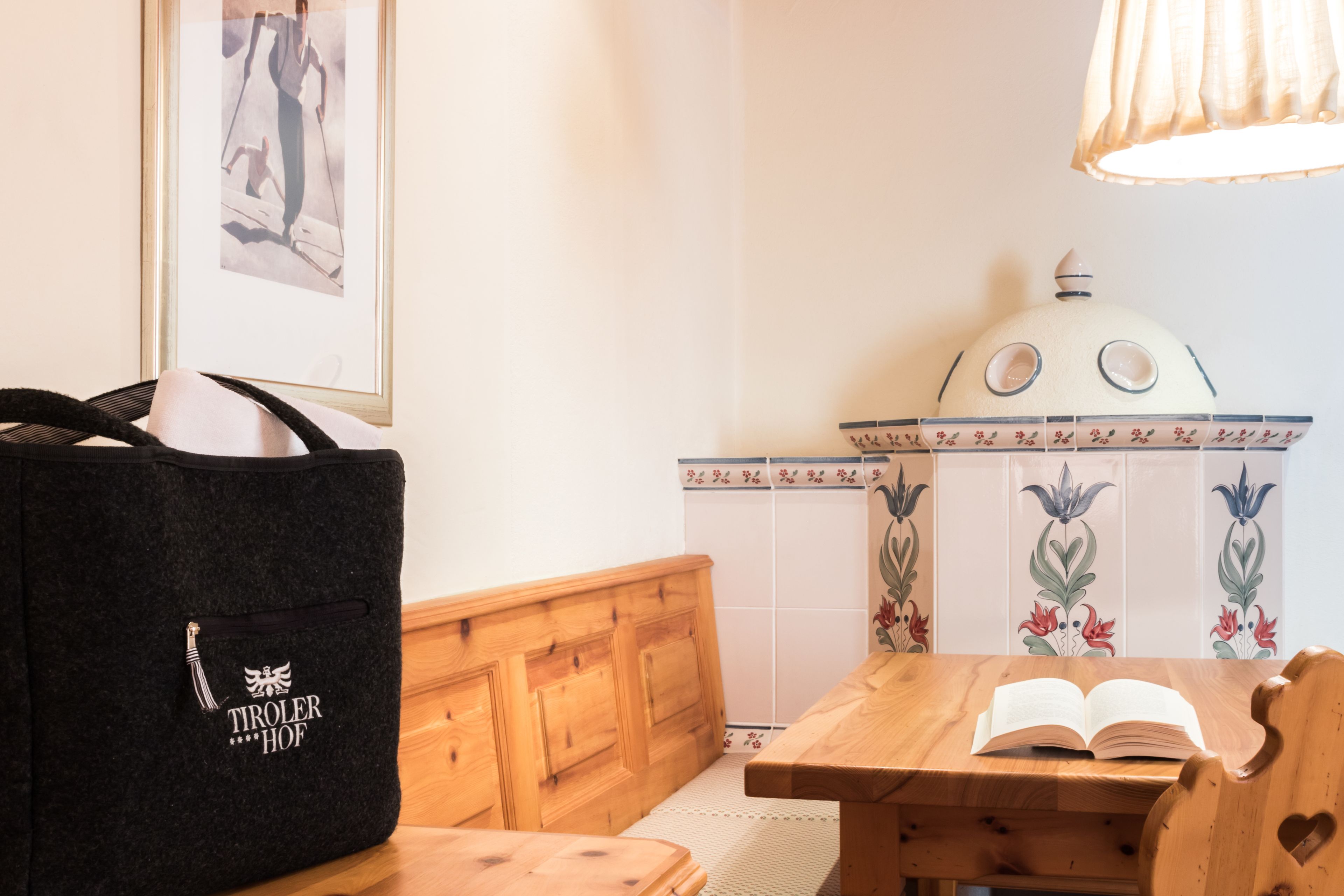 A wooden bench with a black bag and an open book on a table.