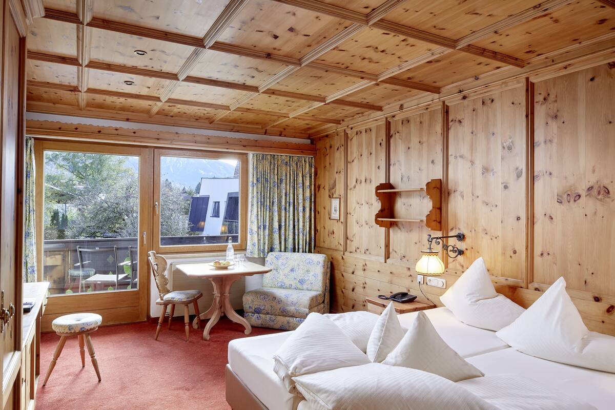Ein Zimmer mit Holzwänden, einem Bett, einem Schreibtisch, einem Stuhl und einem Fenster.
