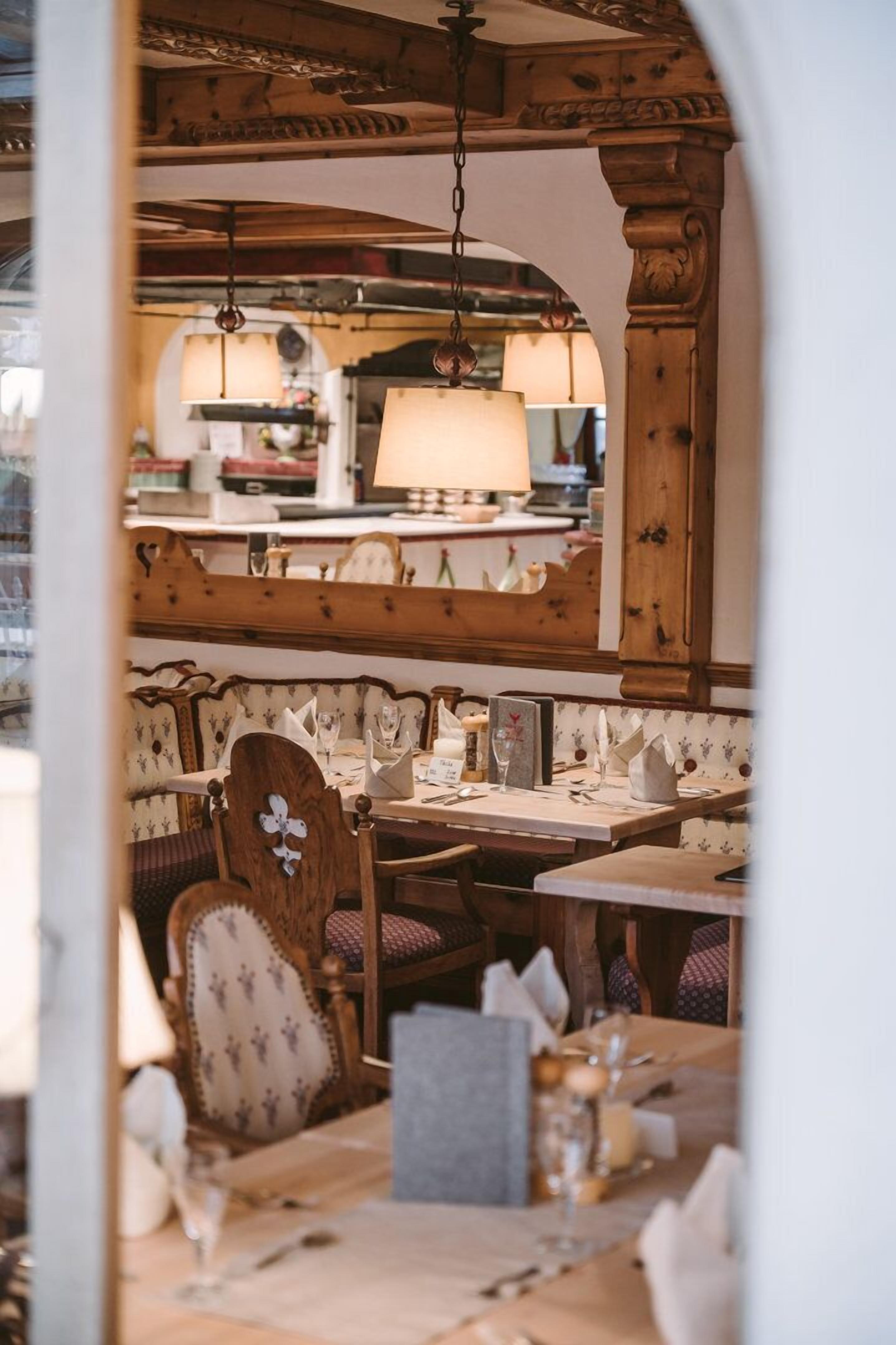 A restaurant interior with wooden furniture, hanging lamps, and a cozy ambiance.