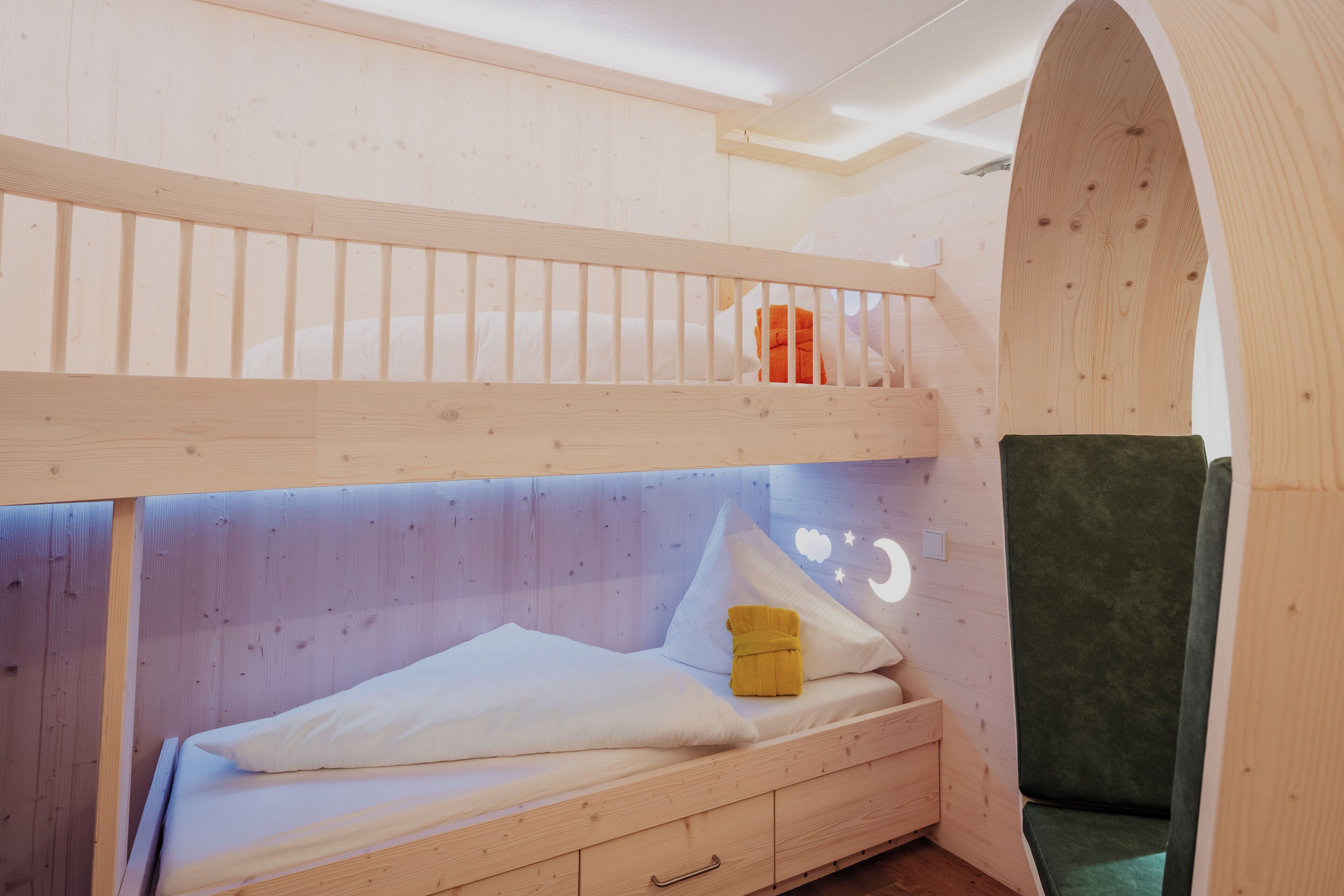 Un letto a castello con un letto inferiore, un comodino, una sedia verde e un arco in legno.