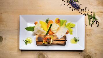 A white rectangular plate with a variety of vegetables and herbs on a wooden surface.