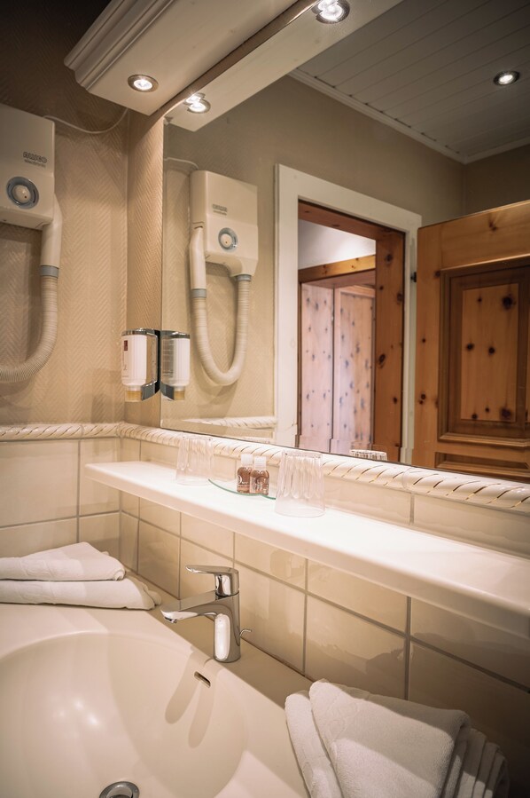 A bathroom with a large bathtub, a mirror, a towel rack, and a hand dryer.