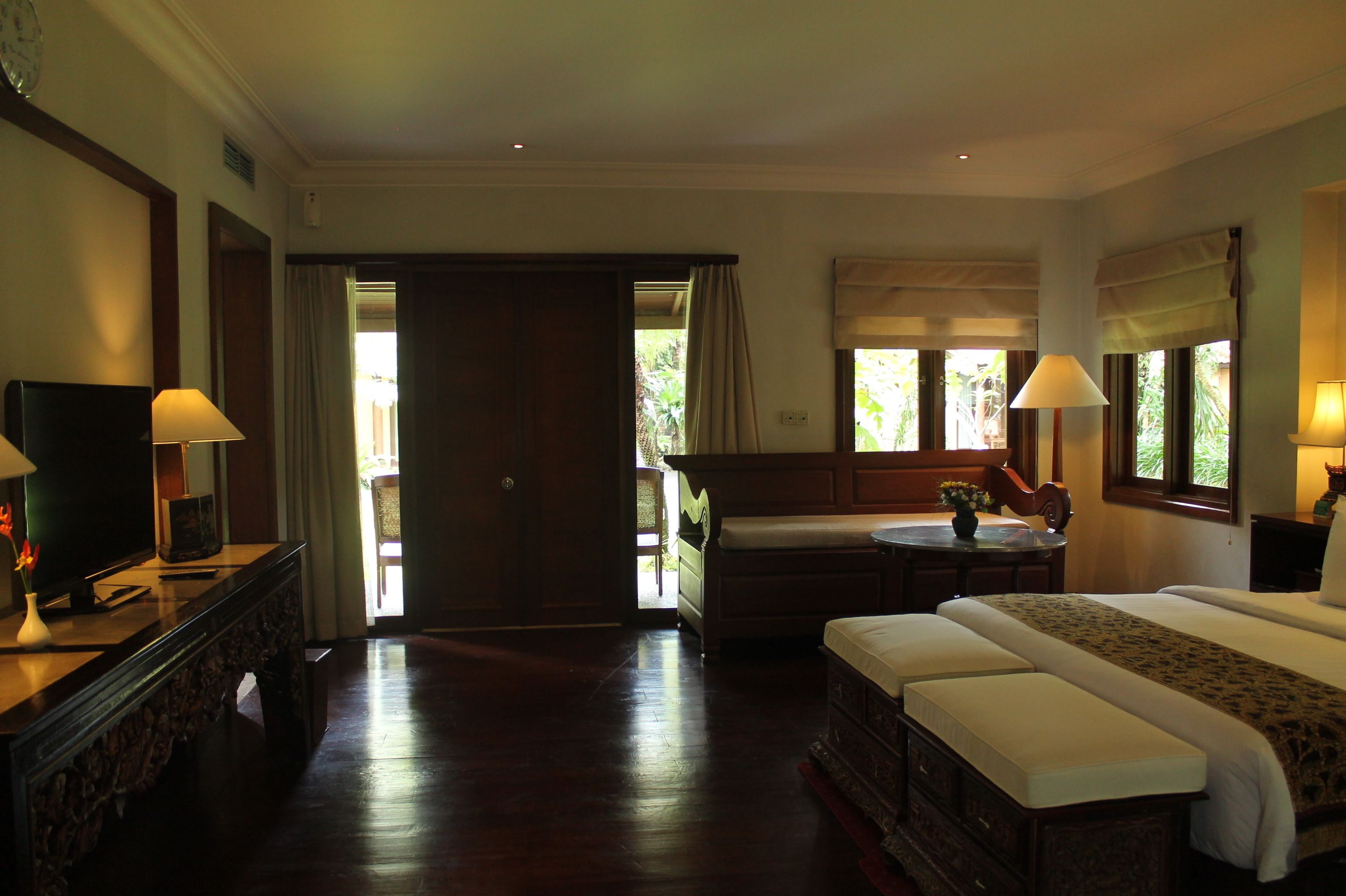 Habitación de hotel con una cama grande, televisión, escritorio con lámpara y vistas al exterior.