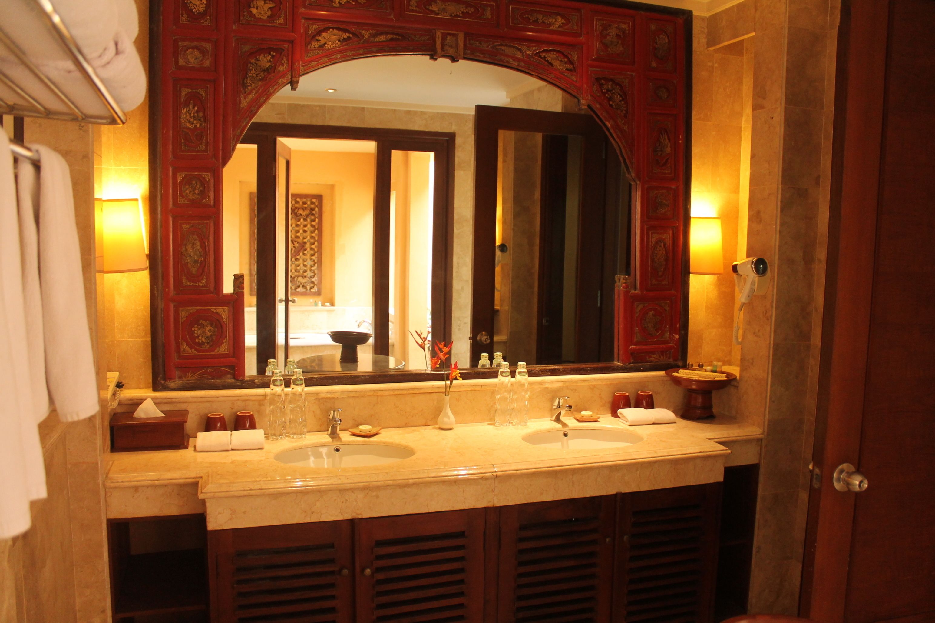 A bathroom with a double sink, a large mirror, and a red decorative frame.