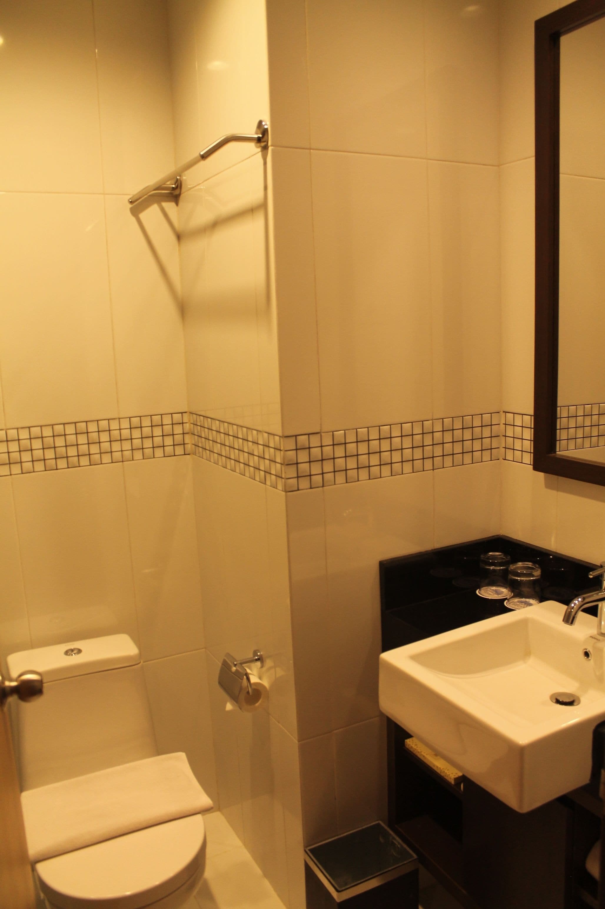 A bathroom with a toilet, sink, and a mirror.