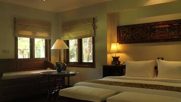 Quarto de hotel com uma cama, duas mesas de cabeceira, um banco e uma janela com vista para o verde.