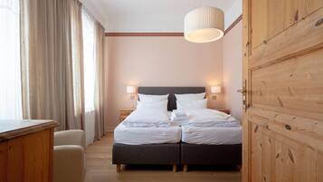 Ein Hotelzimmer mit Doppelbett, Nachttischlampen, einem Holzschrank und einem Schreibtisch.
