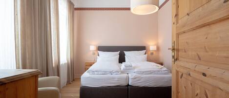 Una habitación de hotel con cama doble, lámparas de noche, un armario de madera y un escritorio.