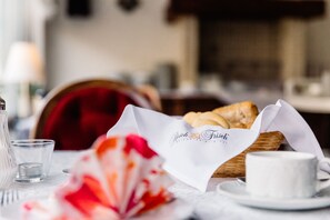 Una mesa de comedor con una cesta de pan, una taza y un vaso.