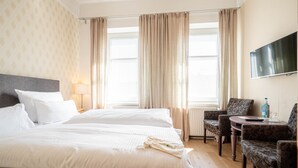 Habitación de hotel con dos camas, televisor, una mesita y una silla.