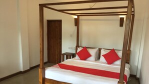 A four-poster bed with a wooden frame and white bedding, red pillows, and a red and white striped blanket.