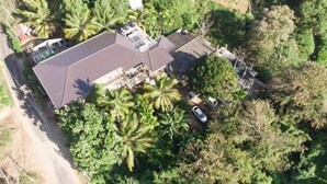 An aerial view of a residential property with a large house, a garage, and a driveway.