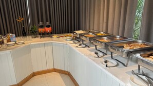A buffet setup with various food items and condiments.