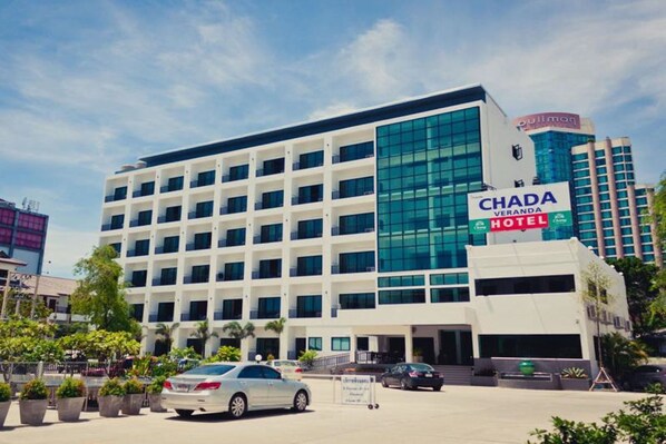 A multi-story hotel with a modern design, featuring a prominent glass facade and a sign for 'Chada Veranda Hotel'.