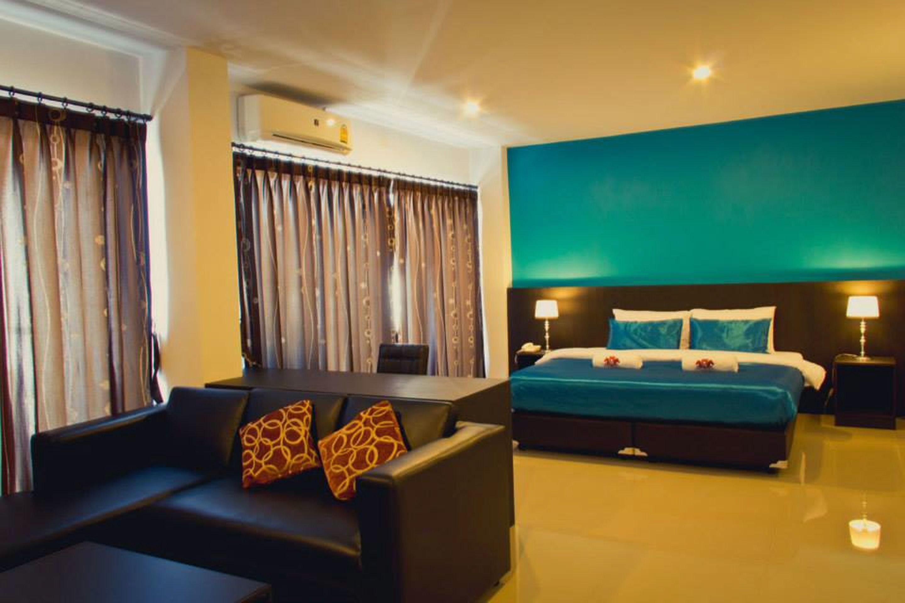 Una habitación de hotel con cama, sofá, escritorio y cortinas.
