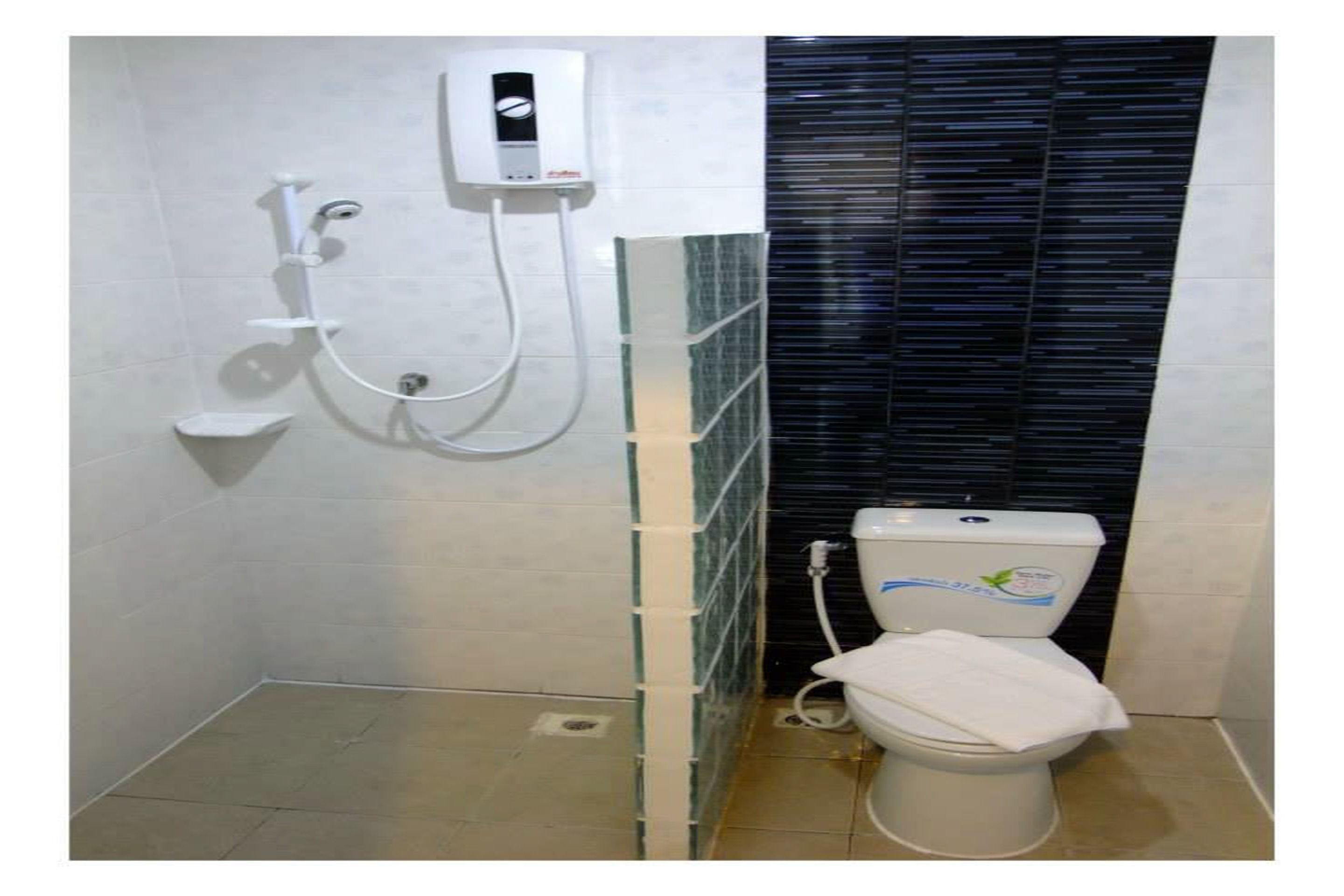 A bathroom with a toilet, a shower unit, and a tiled wall.