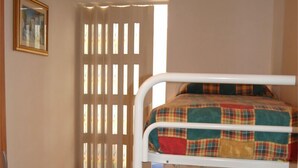 Habitación con literas, un armario de madera y una ventana con persianas.