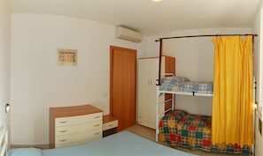 Une chambre avec un lit superposé, une commode en bois, une armoire et un lit simple.