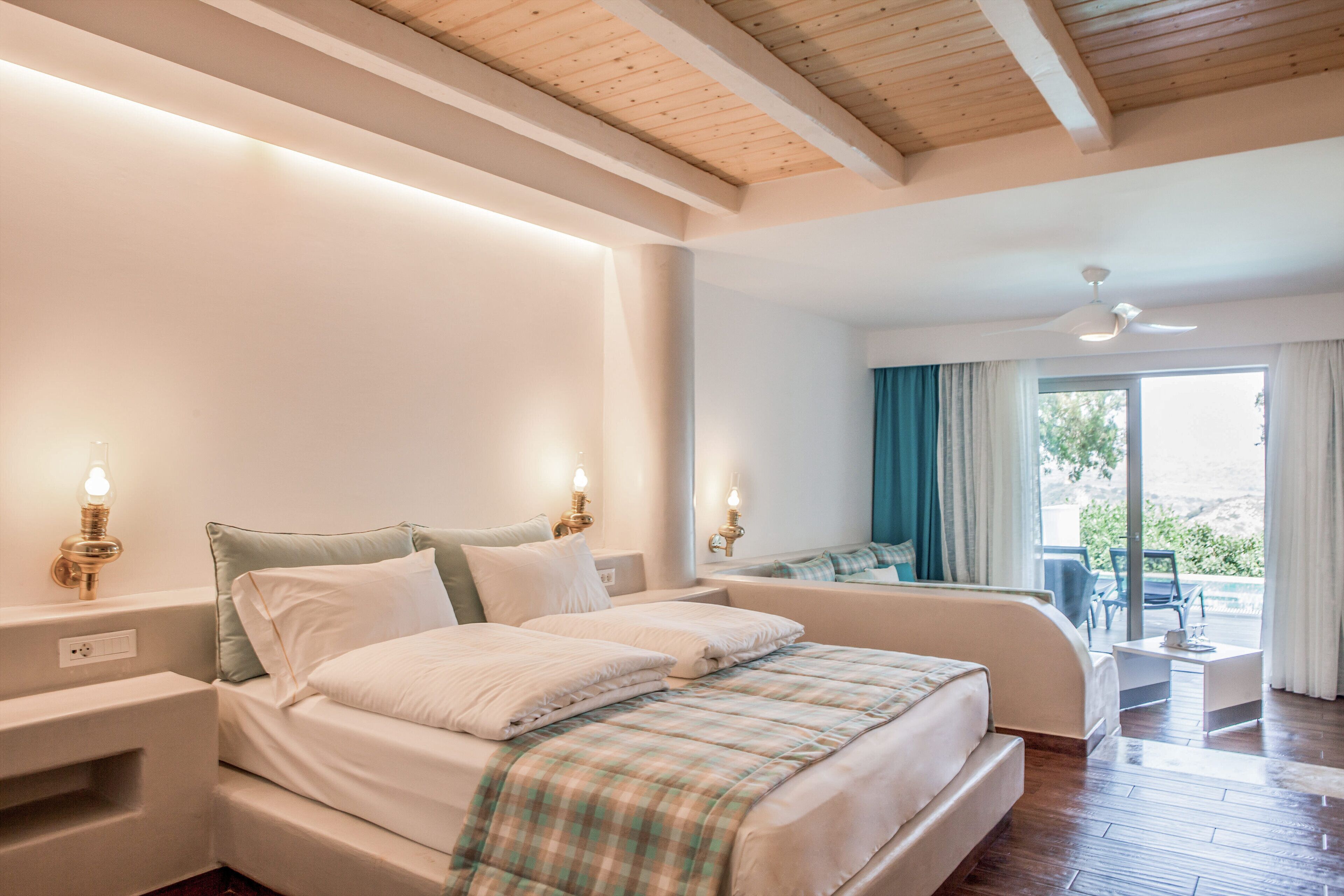 Un dormitorio con una cama grande, mesitas de noche, un ventilador de techo y vistas al exterior.