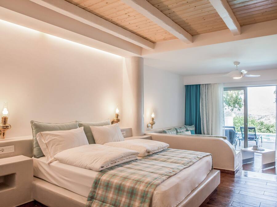 Un dormitorio con una cama grande, mesitas de noche, un ventilador de techo y vistas al exterior.