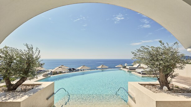 On peut admirer une piscine aux eaux cristallines, avec une vue imprenable sur la mer, entourée de chaises longues et de parasols.